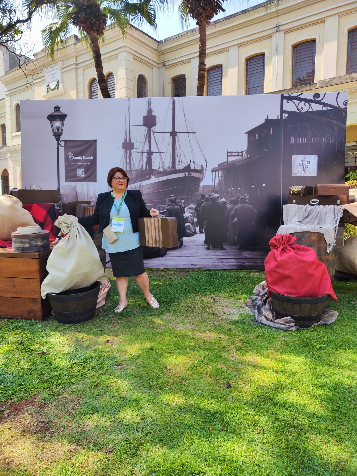 Marina Martello, Italian genealogist, at a genealogy conference before a ship mural with emigrant suitcases