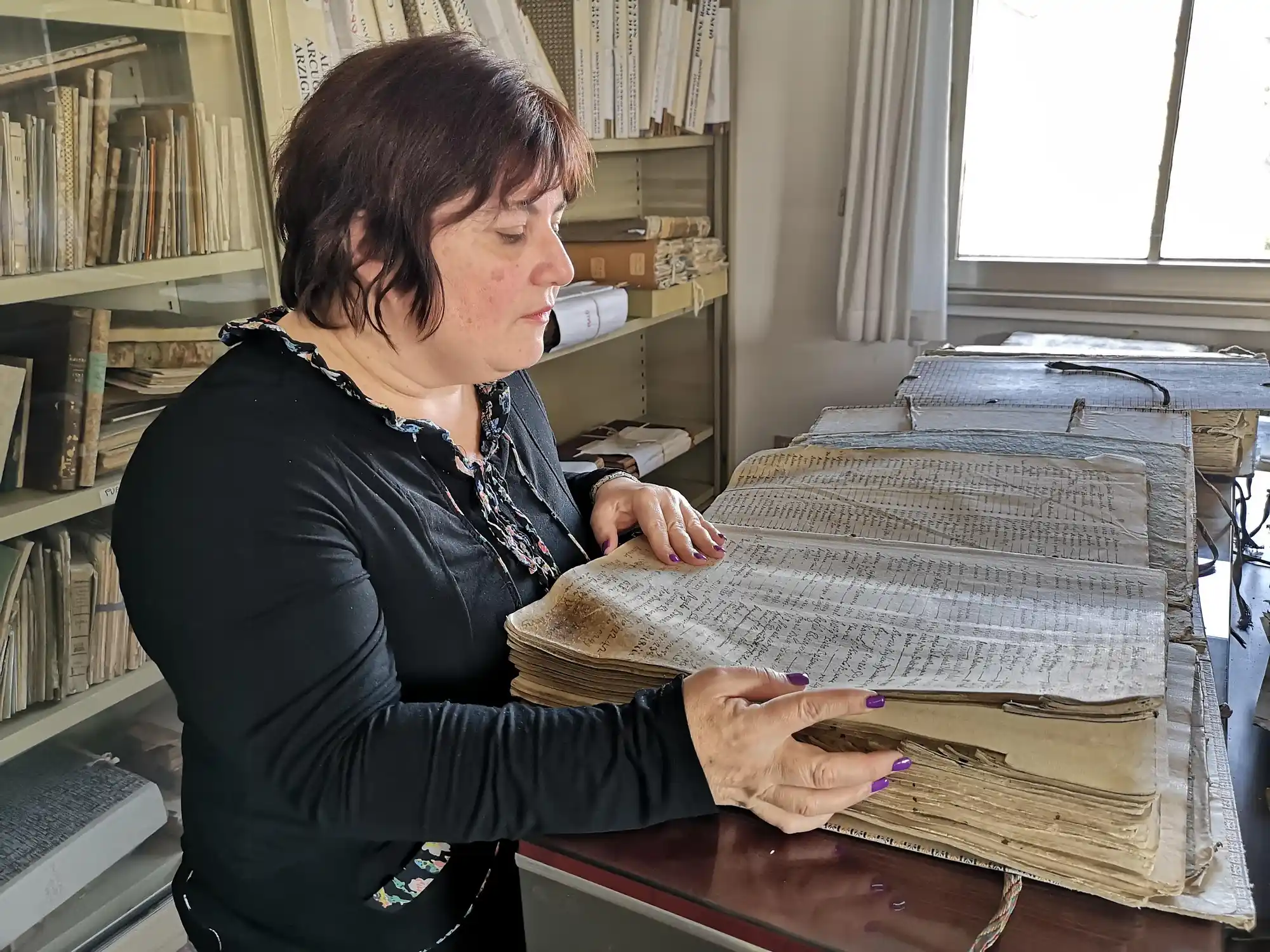 Marina Martello studying historical parish books in an Italian archive